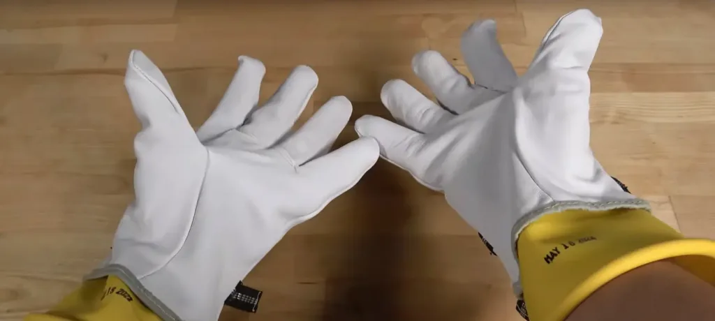 image of hands wearing rubber gloves and protective over-gloves for working with high-voltage hybrid batteries